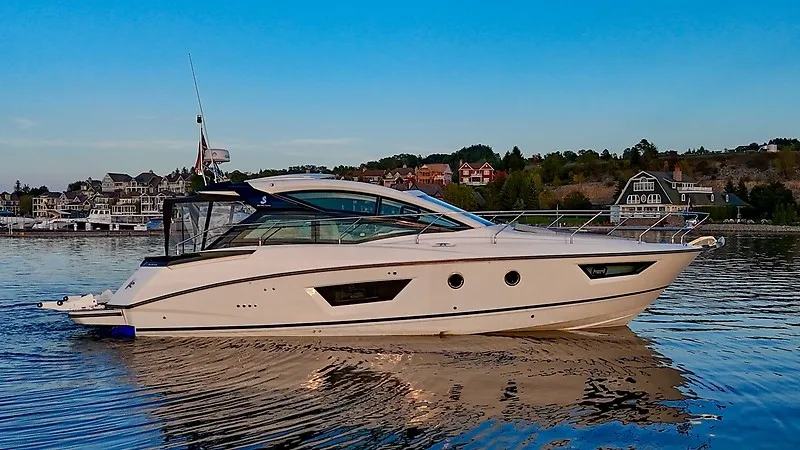 Slide: The Image of The 2020 Beneteau Gran Turismo 40 glides on calm water against a scenic coastal backdrop. - 1