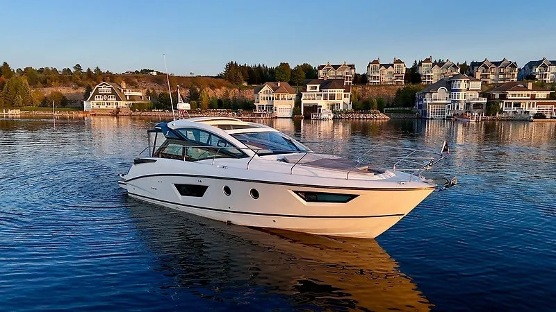 The Image of 2020 Beneteau Gran Turismo 40 on calm water near a coastal town. - 0