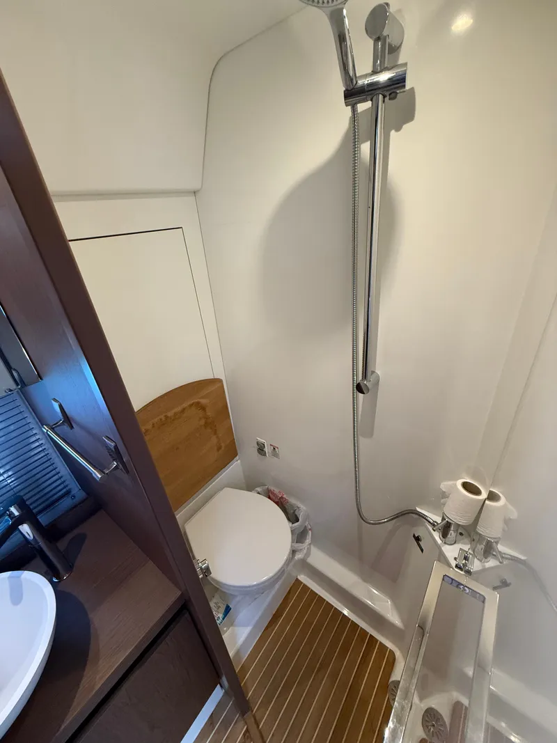 Slide: The Image of The cabin of a 2020 Beneteau Gran Turismo 40 features a compact shower with wooden accents. - 48