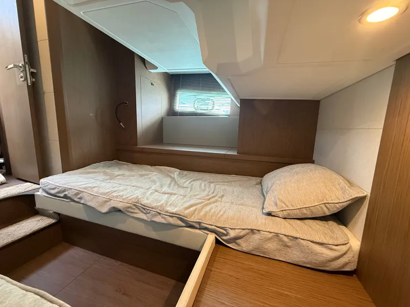 Slide: The Image of The cabin of the 2020 Beneteau Gran Turismo 40 features a single bed, window, and wood paneling. - 35