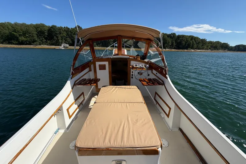 Slide: The Image of 1978 Wasque 26 boat interior with cushioned seating, wooden accents, and scenic water view. - 24