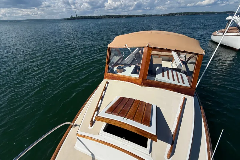 Slide: The Image of 1978 Wasque 26 boat on calm water, featuring classic wooden details and beige canopy. - 21