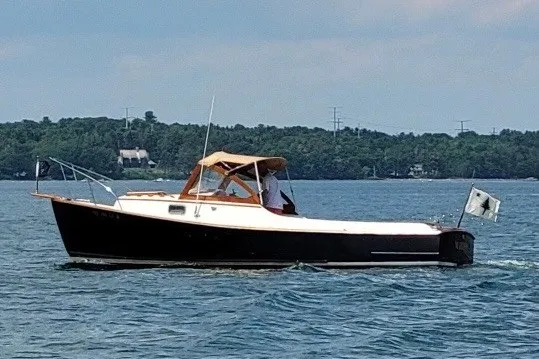 Slide: The Image of 1978 Wasque 26 boat cruising on a calm lake with a scenic forest backdrop. - 26