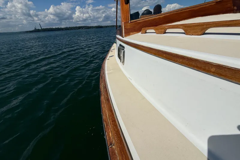 Slide: The Image of 1978 Wasque 26 boat deck with wooden trim on calm water under cloudy sky. - 22