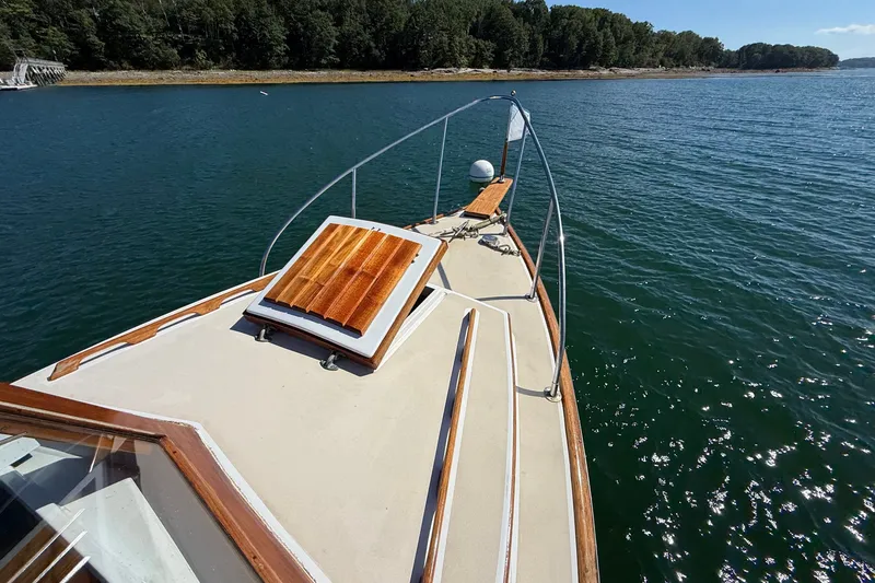 Slide: The Image of 1978 Wasque 26 boat on calm water, featuring a wooden deck and scenic shoreline. - 18
