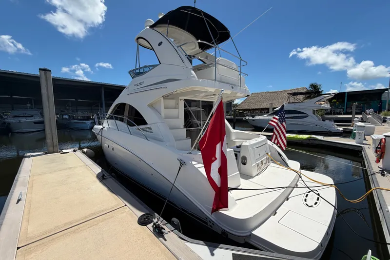Slide: The Image of 2010 Sea Ray 390 Sedan Bridge yacht docked at marina, flags displayed, clear sky. - 1