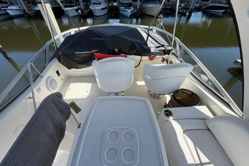 Slide: The Image of 2010 Sea Ray 390 Sedan Bridge cockpit with white seating and covered controls. - 36