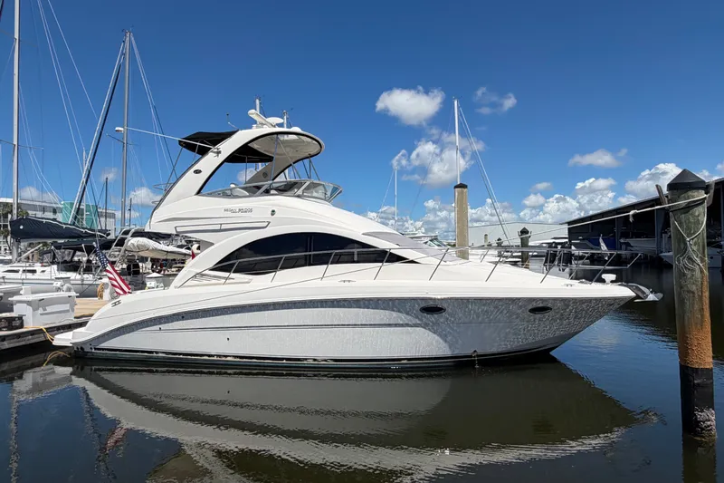 The Image of 2010 Sea Ray 390 Sedan Bridge yacht docked in a marina under a clear blue sky. - 0