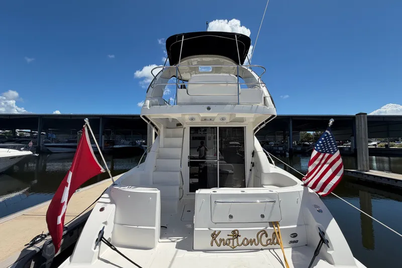 Slide: The Image of 2010 Sea Ray 390 Sedan Bridge yacht docked, featuring flags and a clear blue sky. - 16
