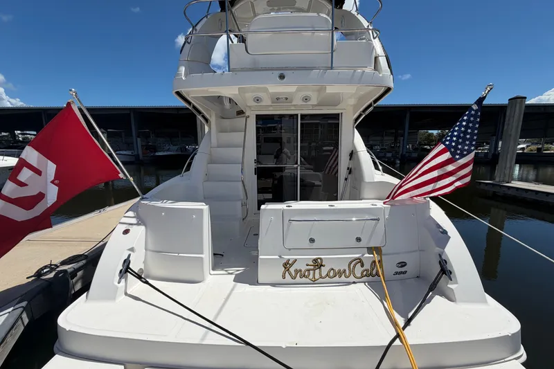 Slide: The Image of 2010 Sea Ray 390 Sedan Bridge yacht docked, featuring flags and spacious deck. - 13