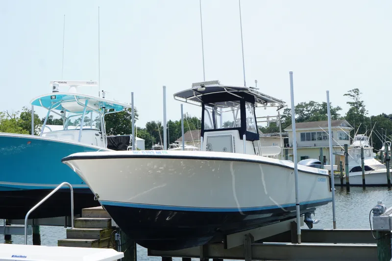 The Image of 2006 Contender 27 Open boat docked at marina, surrounded by other vessels. - 1