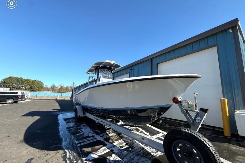 Slide: The Image of 2006 Contender 27 Open boat on trailer, parked outside a blue building. - 14