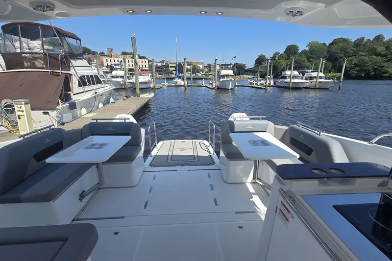 Slide: The Image of 2025 Four Winns TH36 yacht interior with seating and tables, docked at a marina. - 5