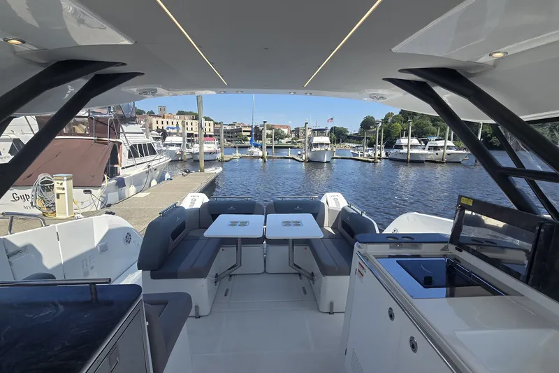 Slide: The Image of 2025 Four Winns TH36 yacht interior with seating and kitchenette, docked at a marina. - 6