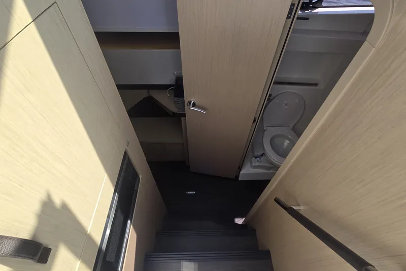 Slide: The Image of Interior view of 2025 Four Winns TH36 yacht, featuring a compact bathroom and wooden finishes. - 25