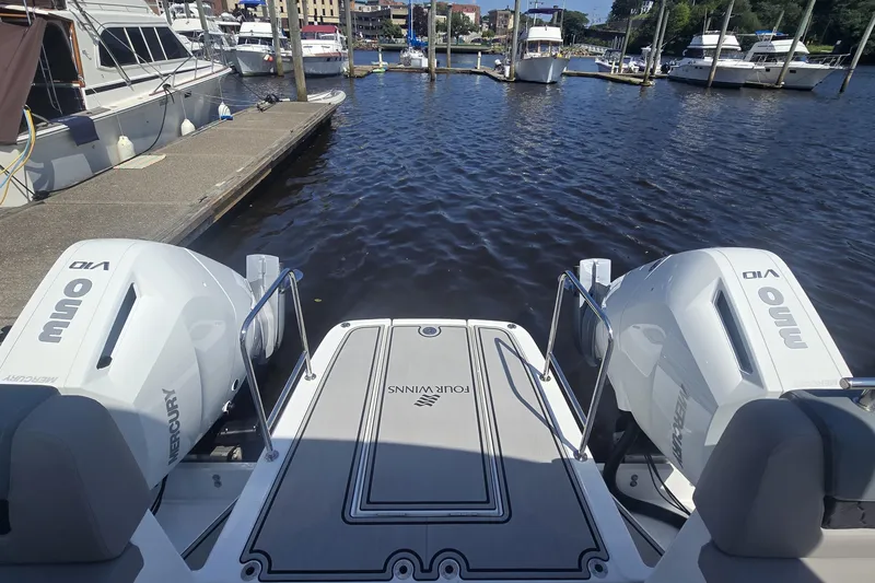 Slide: The Image of 2025 Four Winns TH36 boat with dual Mercury outboard engines docked at marina. - 2