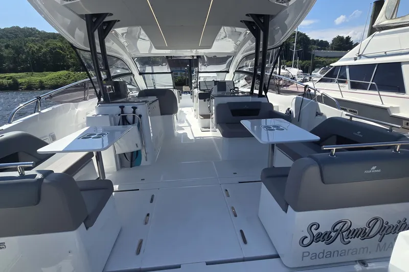 Slide: The Image of 2025 Four Winns TH36 yacht interior with seating and tables, docked by a river. - 3