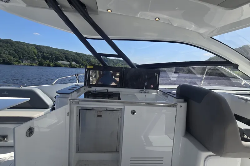 Slide: The Image of 2025 Four Winns TH36 yacht interior with kitchenette, overlooking serene lake and lush greenery. - 10