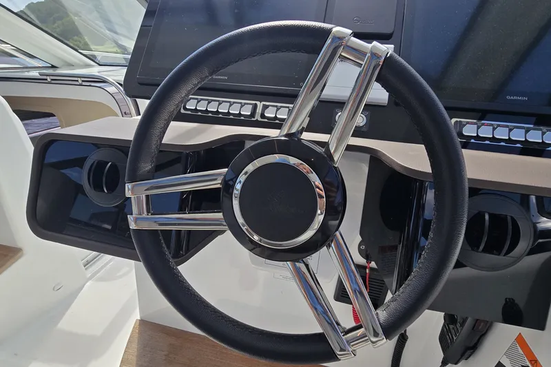 Slide: The Image of Steering wheel of 2025 Four Winns TH36 boat, featuring modern dashboard controls. - 14