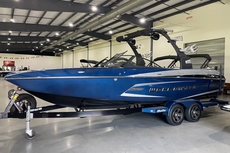 The Image of 2015 Malibu Wakesetter 24 MXZ boat in showroom, blue exterior, on trailer. - 1
