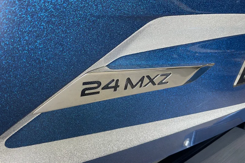 Slide: The Image of 2015 Malibu Wakesetter 24 MXZ emblem on metallic blue surface. - 2