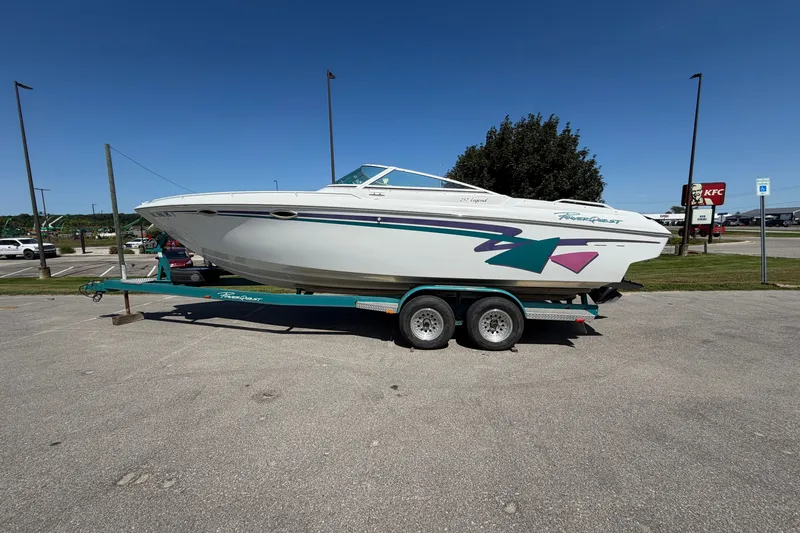 The Image of 1995 Powerquest 257 Legend boat on trailer in parking lot, clear sky background. - 1