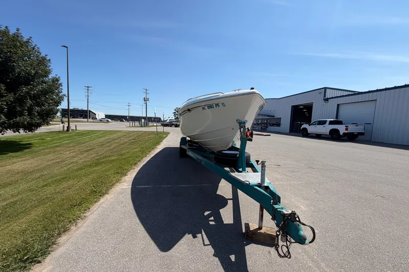 Slide: The Image of 1995 Powerquest 257 Legend boat on trailer, parked near industrial buildings under clear blue sky. - 7