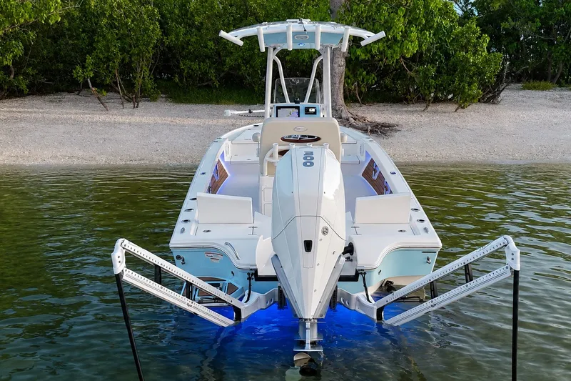 Slide: The Image of 2023 Pathfinder 2500 Hybrid boat docked near a sandy shore with lush greenery. - 11