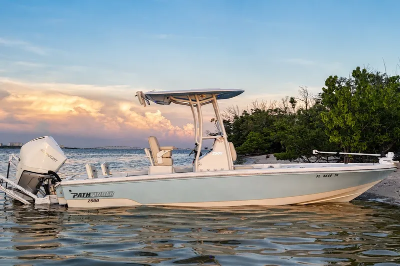 Slide: The Image of 2023 Pathfinder 2500 Hybrid boat on calm water at sunset, near lush shoreline. - 4
