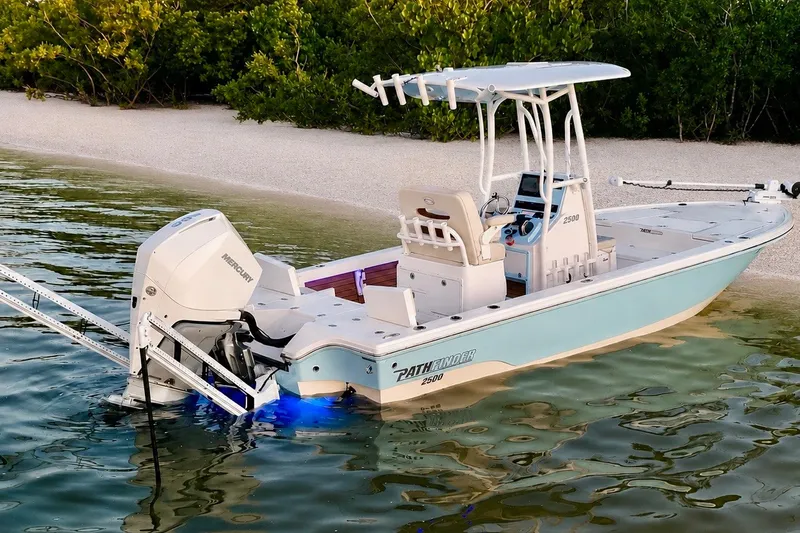 Slide: The Image of 2023 Pathfinder 2500 Hybrid boat docked near a sandy shore with lush greenery. - 15