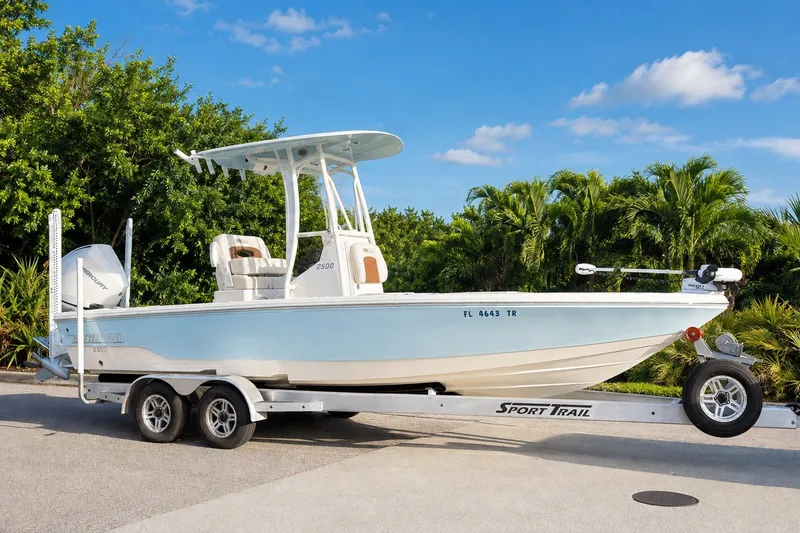 Slide: The Image of 2023 Pathfinder 2500 Hybrid boat on trailer, parked near lush greenery. - 22