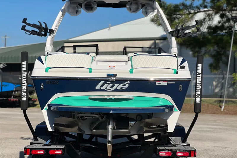 Slide: The Image of 2023 Tigé 21ZX boat with teal accents on a trailer, rear view. - 3