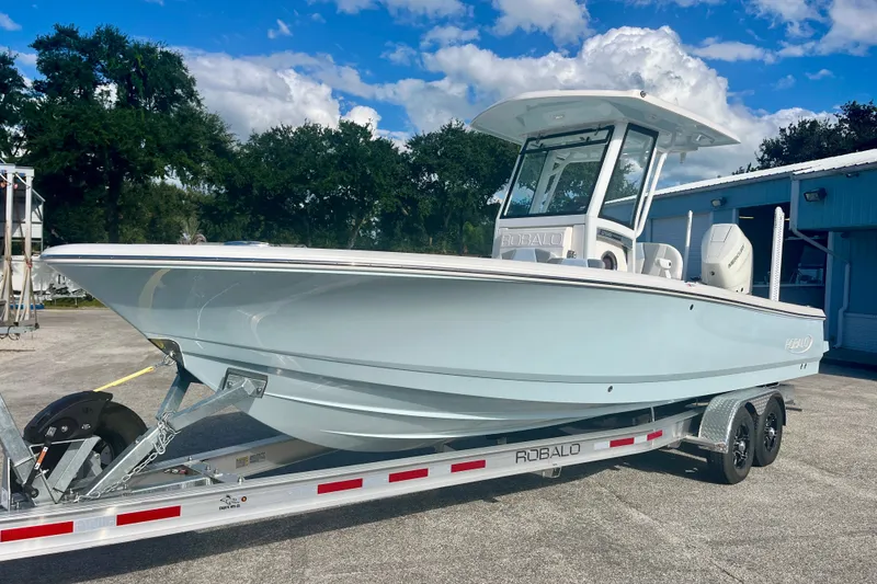 The Image of 2027 Robalo 266 Cayman boat on trailer, parked outdoors under a blue sky. - 0