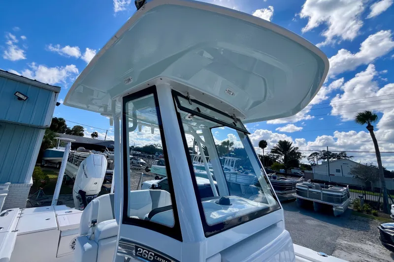 Slide: The Image of 2027 Robalo 266 Cayman boat with T-top, parked outdoors under a blue sky. - 29