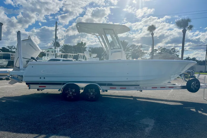 Slide: The Image of 2027 Robalo 266 Cayman boat on trailer under sunny sky with palm trees. - 8