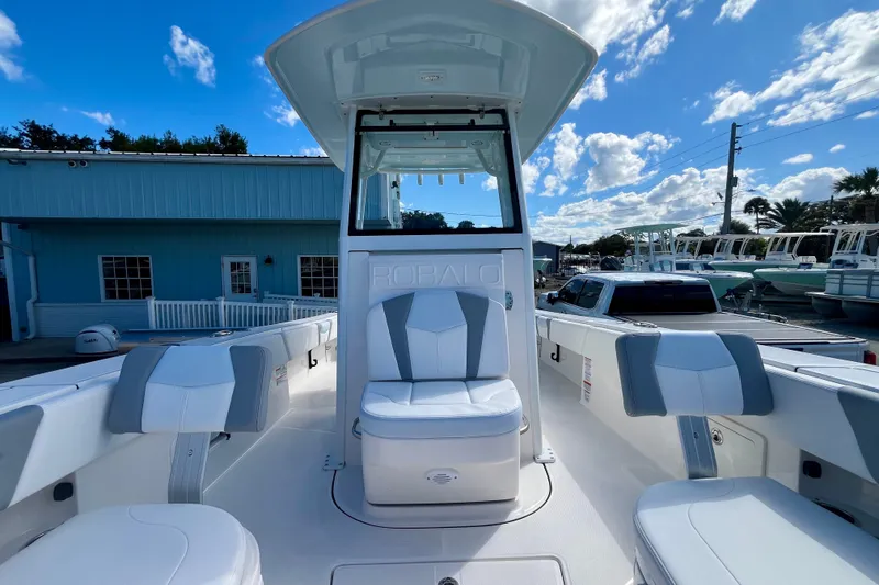 Slide: The Image of 2027 Robalo 266 Cayman boat interior with white and gray seating under a blue sky. - 36