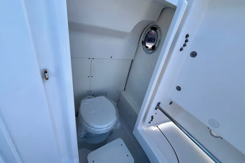 Slide: The Image of 2027 Robalo 266 Cayman boat interior bathroom with toilet and porthole window. - 42