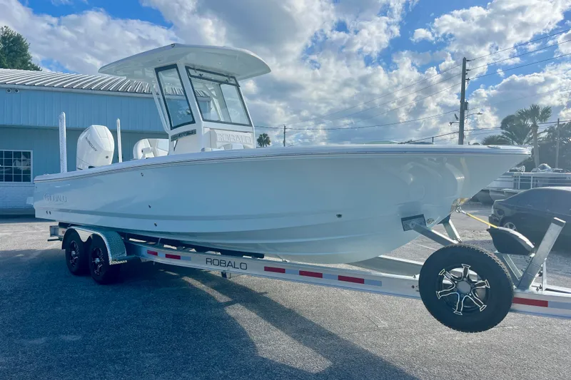 Slide: The Image of 2027 Robalo 266 Cayman boat on trailer under a partly cloudy sky. - 6