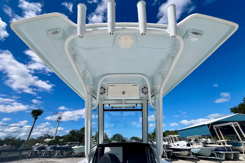 Slide: The Image of 2027 Robalo 266 Cayman boat console with T-top under a clear blue sky. - 27