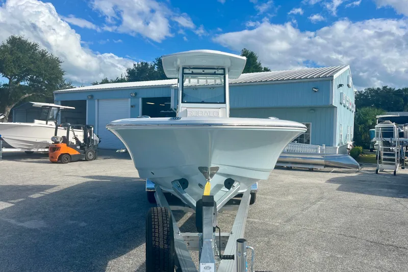 Slide: The Image of 2027 Robalo 266 Cayman boat on trailer, parked outside a blue building under a cloudy sky. - 7