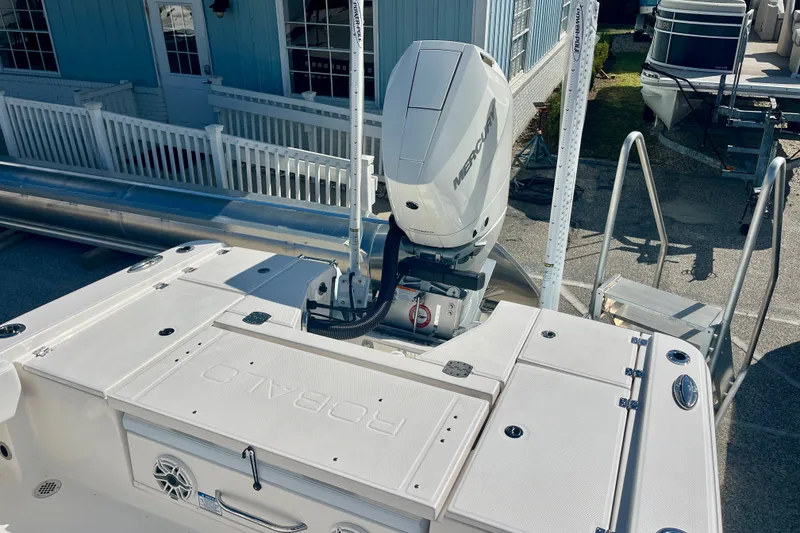 Slide: The Image of 2027 Robalo 266 Cayman boat with Mercury engine, docked near blue building. - 10