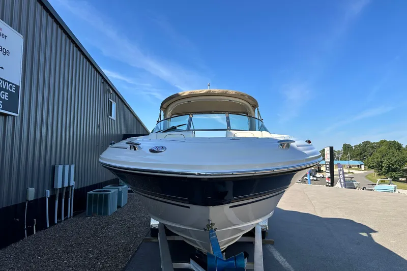 Slide: The Image of 2001 Sea Ray 290 Bowrider boat on trailer, parked beside a metal building under clear blue sky. - 4