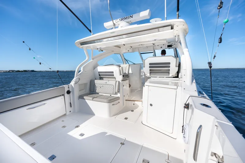 Slide: The Image of 2021 Pursuit DC 365 Dual Console boat on open water, showcasing spacious deck and seating. - 24