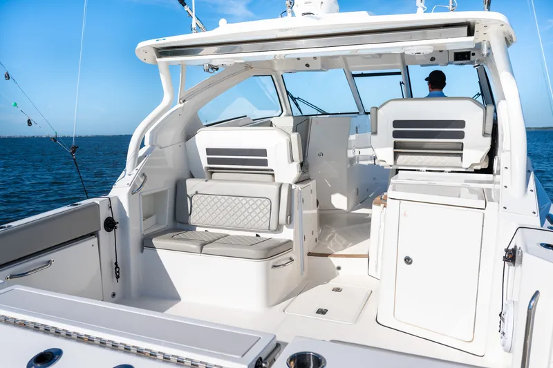 Slide: The Image of 2021 Pursuit DC 365 Dual Console boat interior with seating, ocean view, and fishing rods. - 25
