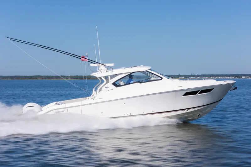 Slide: The Image of 2021 Pursuit DC 365 Dual Console boat cruising on open water under clear blue sky. - 2