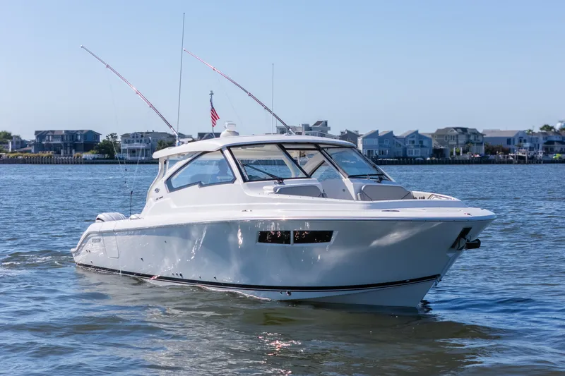 Slide: The Image of 2021 Pursuit DC 365 Dual Console boat cruising on a sunny day near waterfront homes. - 14