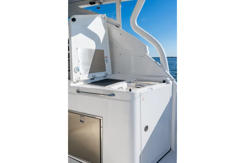 Slide: The Image of 2021 Pursuit DC 365 Dual Console boat kitchen area with sink and storage. - 28