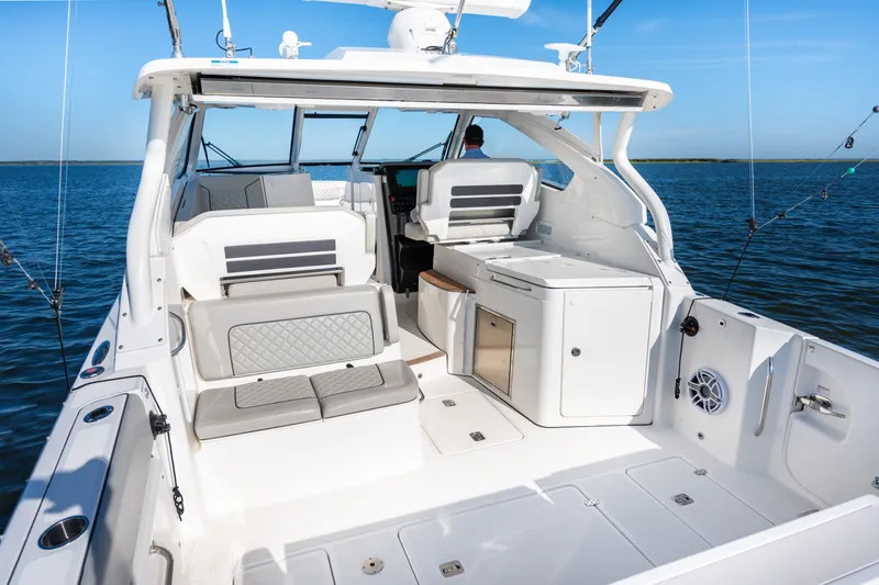 Slide: The Image of 2021 Pursuit DC 365 Dual Console boat interior with seating and storage, on calm water. - 26