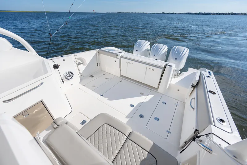 Slide: The Image of 2021 Pursuit DC 365 Dual Console boat with spacious deck and triple engines on open water. - 20