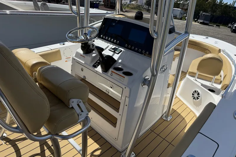 Slide: The Image of 2022 Sportsman Open 212 Center Console boat interior with beige seating and modern controls. - 11